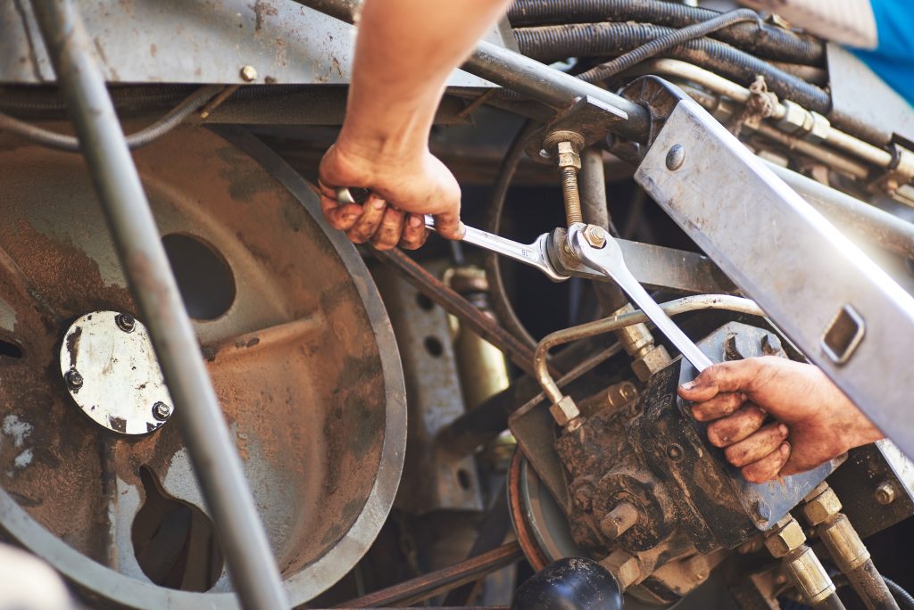 Combine machine service, mechanic repairing motor outdoors