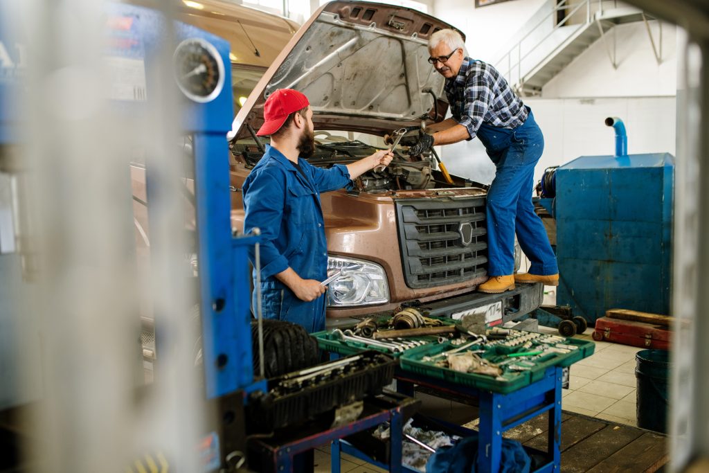 Mechanics inspect a truck in a repair shop, examining the engine.