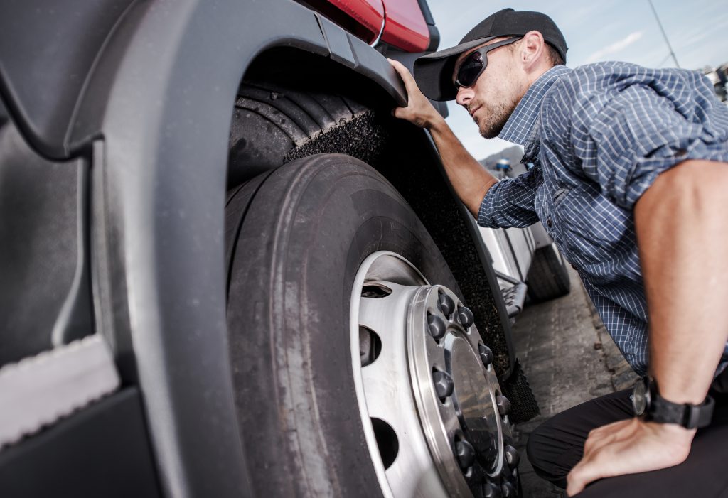 Close-up view of a technician inspecting a truck tire for signs of wear and damage.