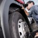 Close-up view of a technician inspecting a truck tire for signs of wear and damage.